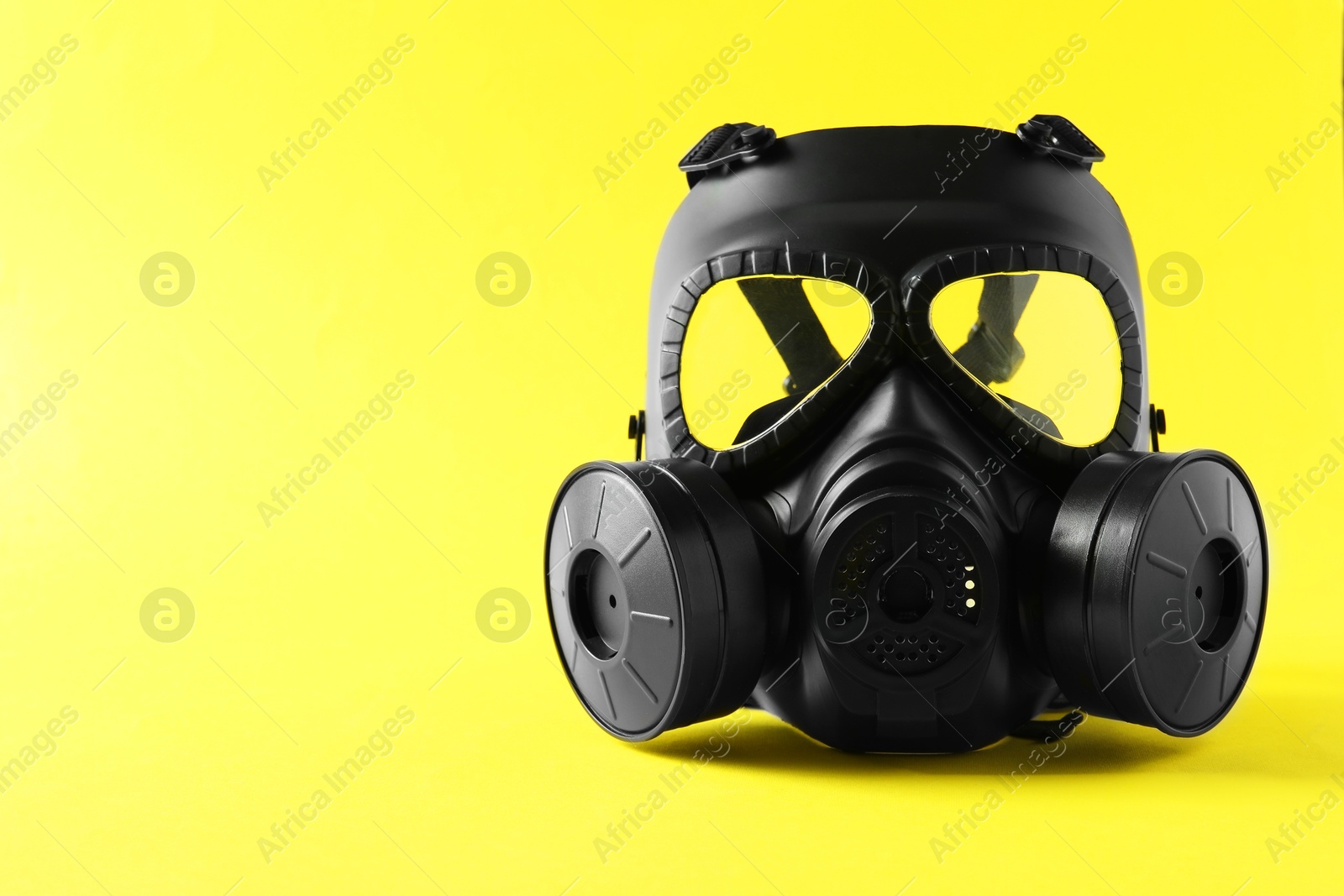 Photo of One gas mask on yellow background, space for text. Safety equipment