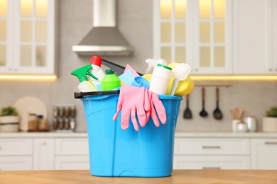 Photo of Cleaning service. Bucket with supplies on table in kitchen