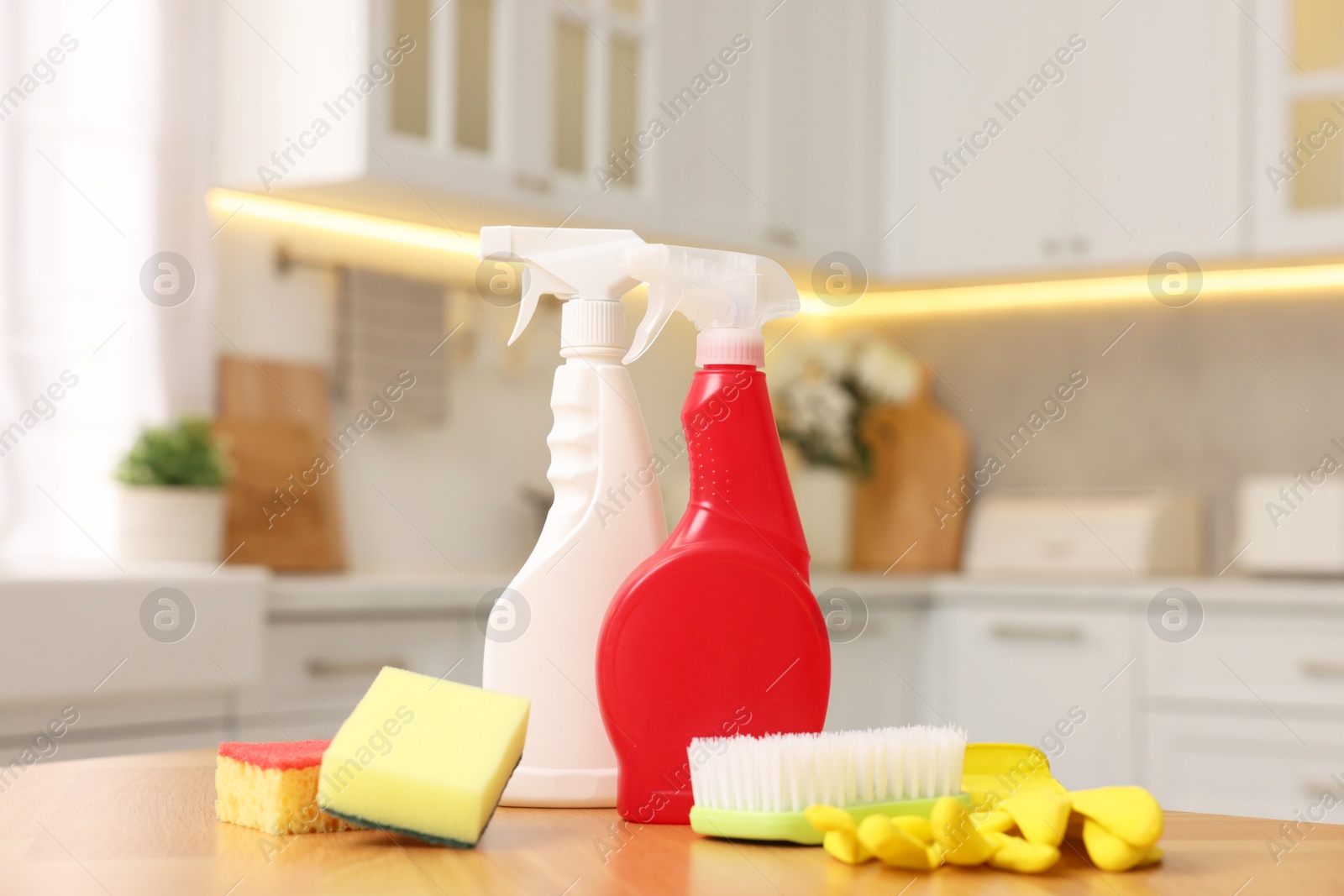 Photo of Cleaning service. Detergents and supplies on table in kitchen