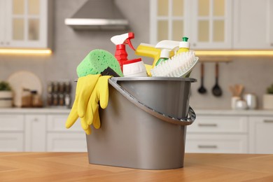 Photo of Cleaning service. Bucket with supplies on table in kitchen