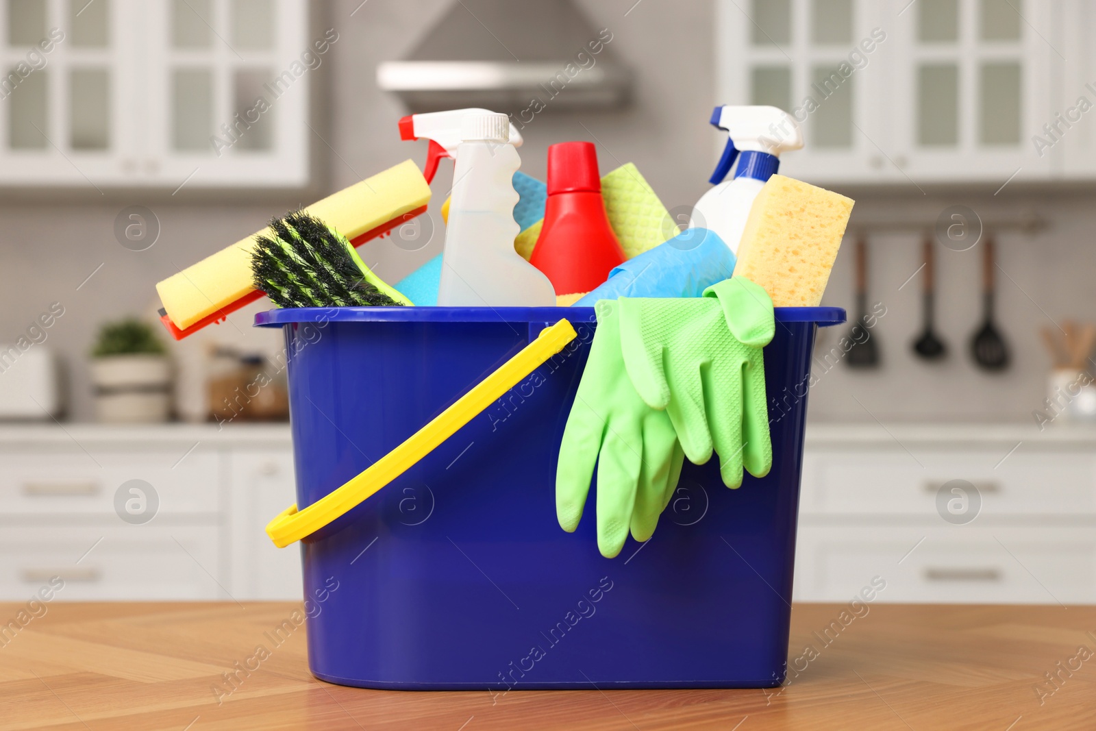 Photo of Cleaning service. Bucket with supplies on table in kitchen