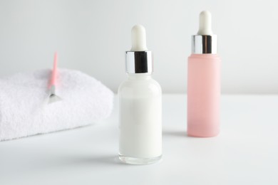 Photo of Bottles of chemical peel, towel and brush on light background, closeup. Peeling procedure