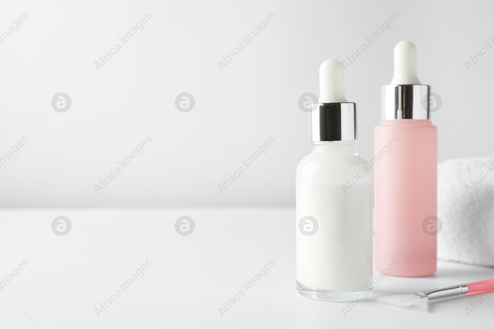 Photo of Bottles of chemical peel and brush on light background, space for text. Peeling procedure