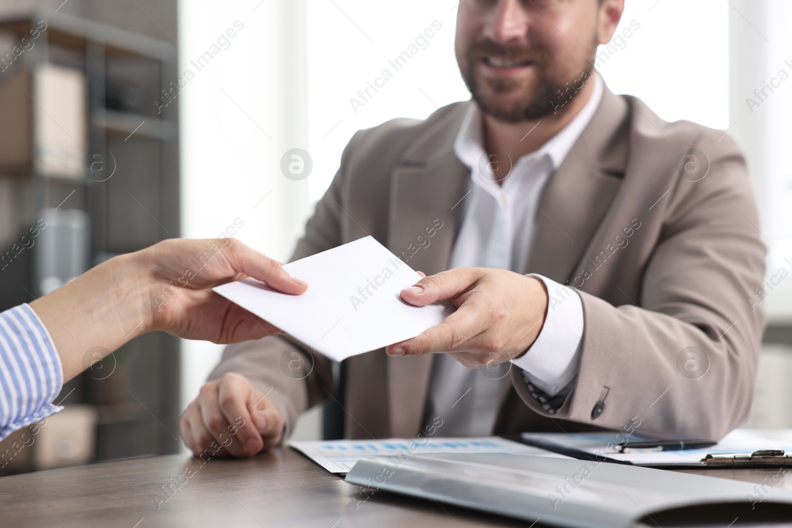 Photo of Boss giving salary in paper envelope to employee indoors, closeup