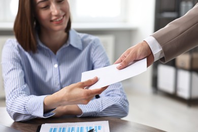 Photo of Boss giving salary in paper envelope to employee indoors