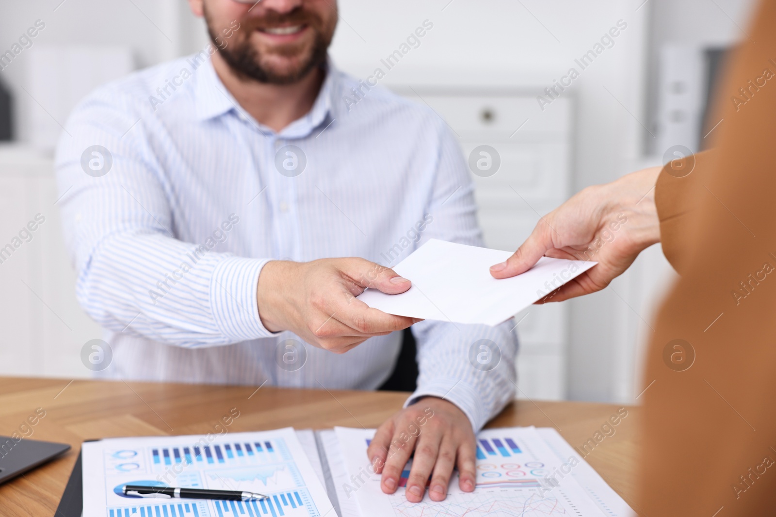 Photo of Boss giving salary in paper envelope to employee indoors, closeup