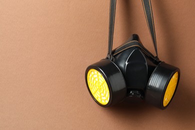 Photo of One respirator mask on brown background. Space for text