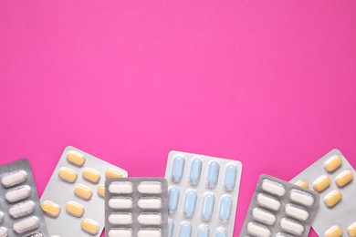 Photo of Different antibiotic pills in blisters on pink background, flat lay. Space for text