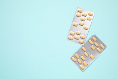 Photo of Antibiotic pills in blisters on light blue background, flat lay. Space for text