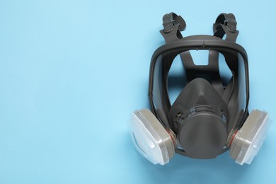 Photo of One full face respirator on light blue background, top view. Space for text