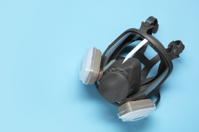 Photo of One full face respirator on light blue background, top view. Space for text