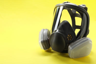 Photo of One full face respirator on yellow background, closeup. Space for text