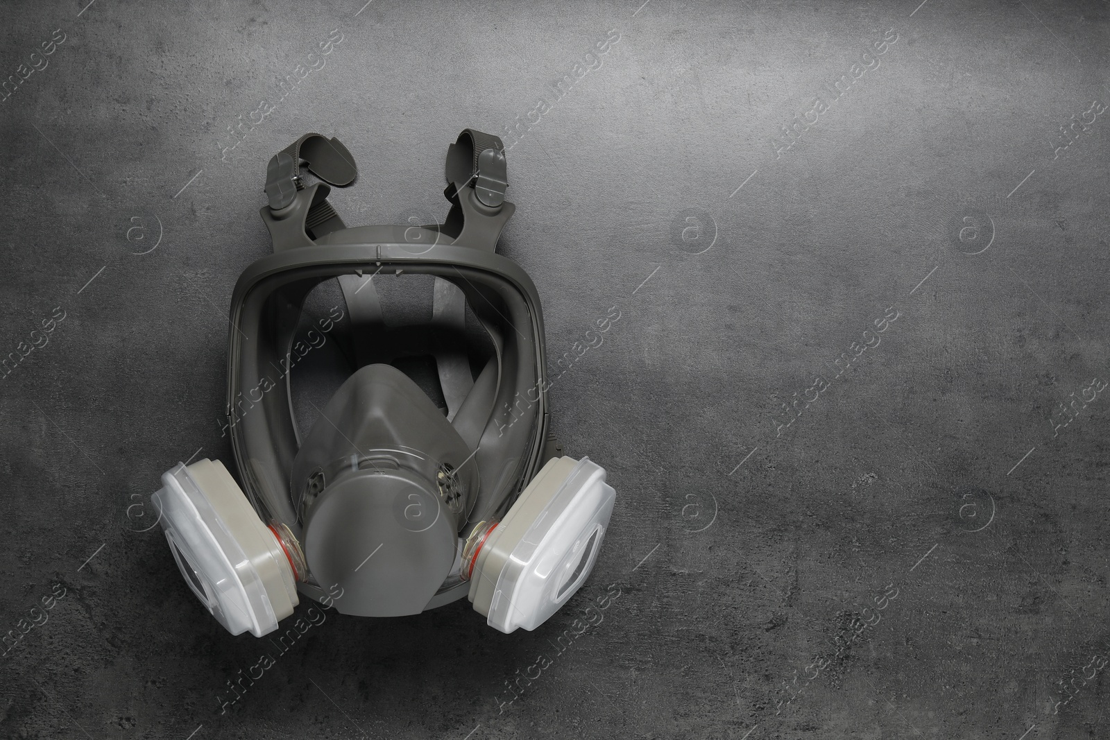 Photo of One full face respirator on dark textured table, top view. Space for text