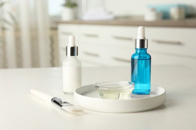 Photo of Peeling procedure. Bottles of chemical peel, bowl with liquid and brush on white table indoors