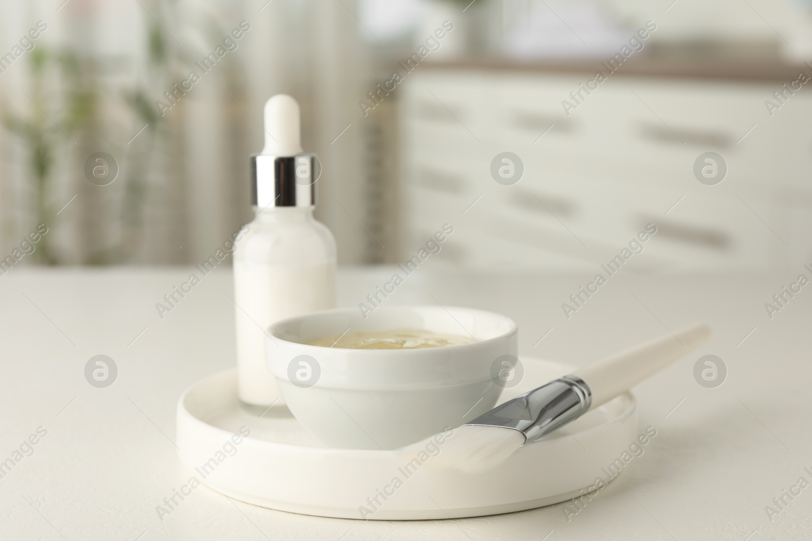 Photo of Peeling procedure. Bottle of chemical peel, bowl with liquid and brush on white table indoors