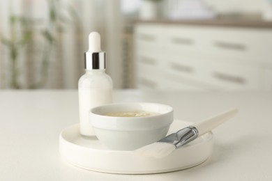 Photo of Peeling procedure. Bottle of chemical peel, bowl with liquid and brush on white table indoors