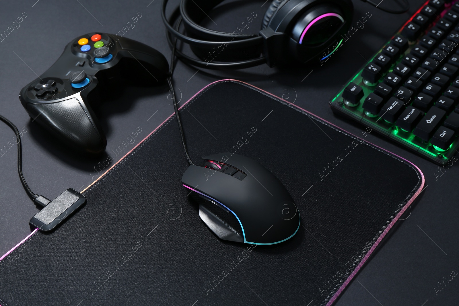 Photo of Computer mouse, RGB keyboard, game controller and headset on black background