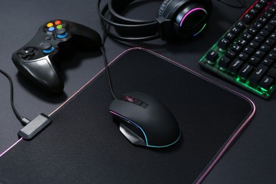 Computer mouse, RGB keyboard, game controller and headset on black background