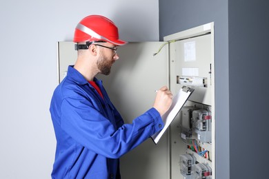 Technician worker with clipboard inspecting electricity meter