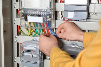Photo of Man checking connecting cables on electricity meter, closeup view