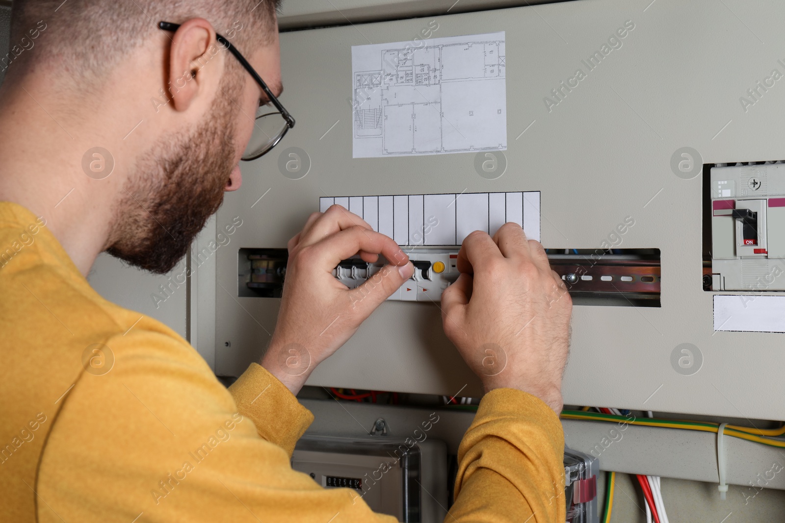 Photo of Man checking electrical fuse board indoors, closeup view