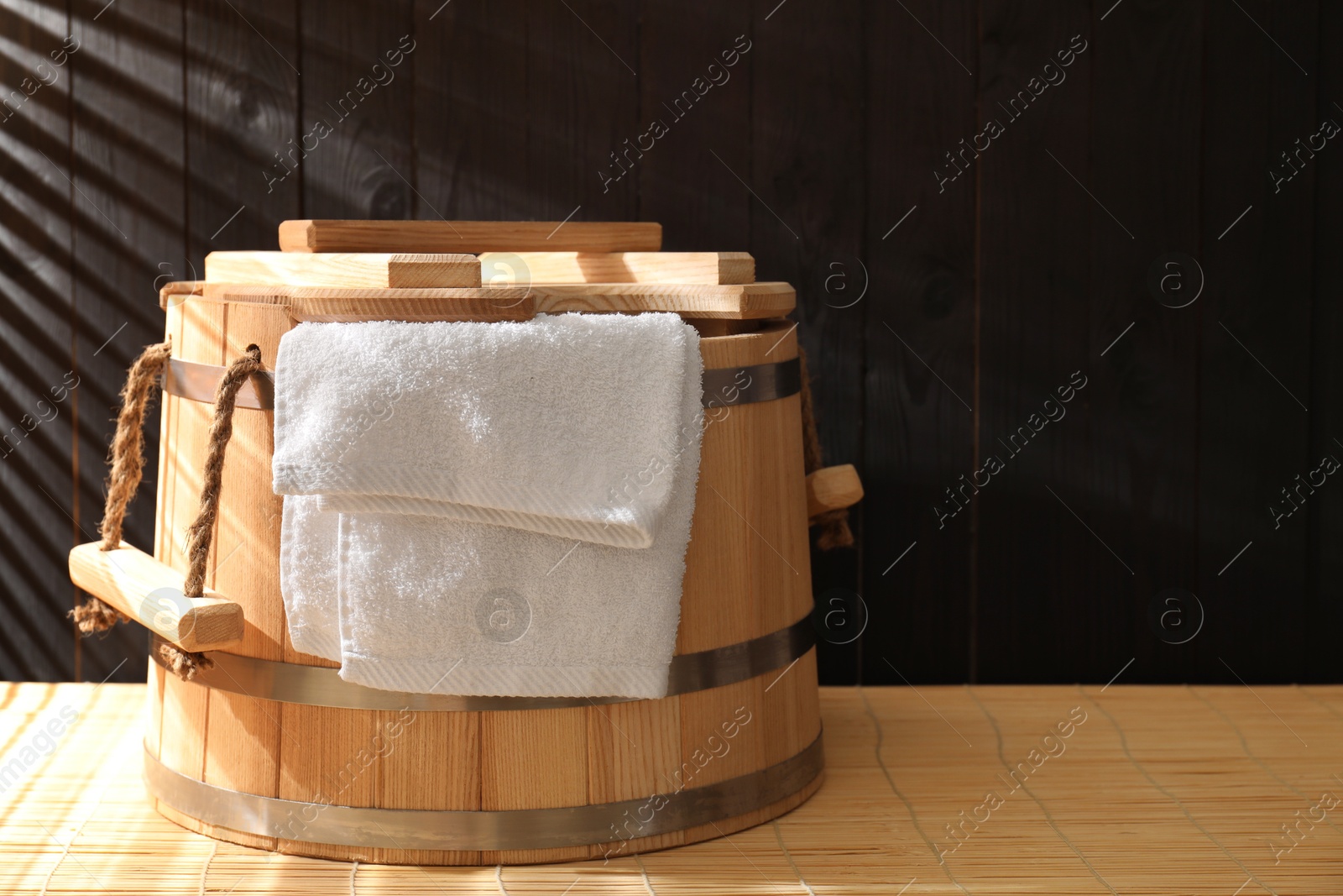 Photo of Sauna equipment. Bucket and towel on bamboo bench, space for text