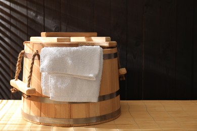 Sauna equipment. Bucket and towel on bamboo bench, space for text