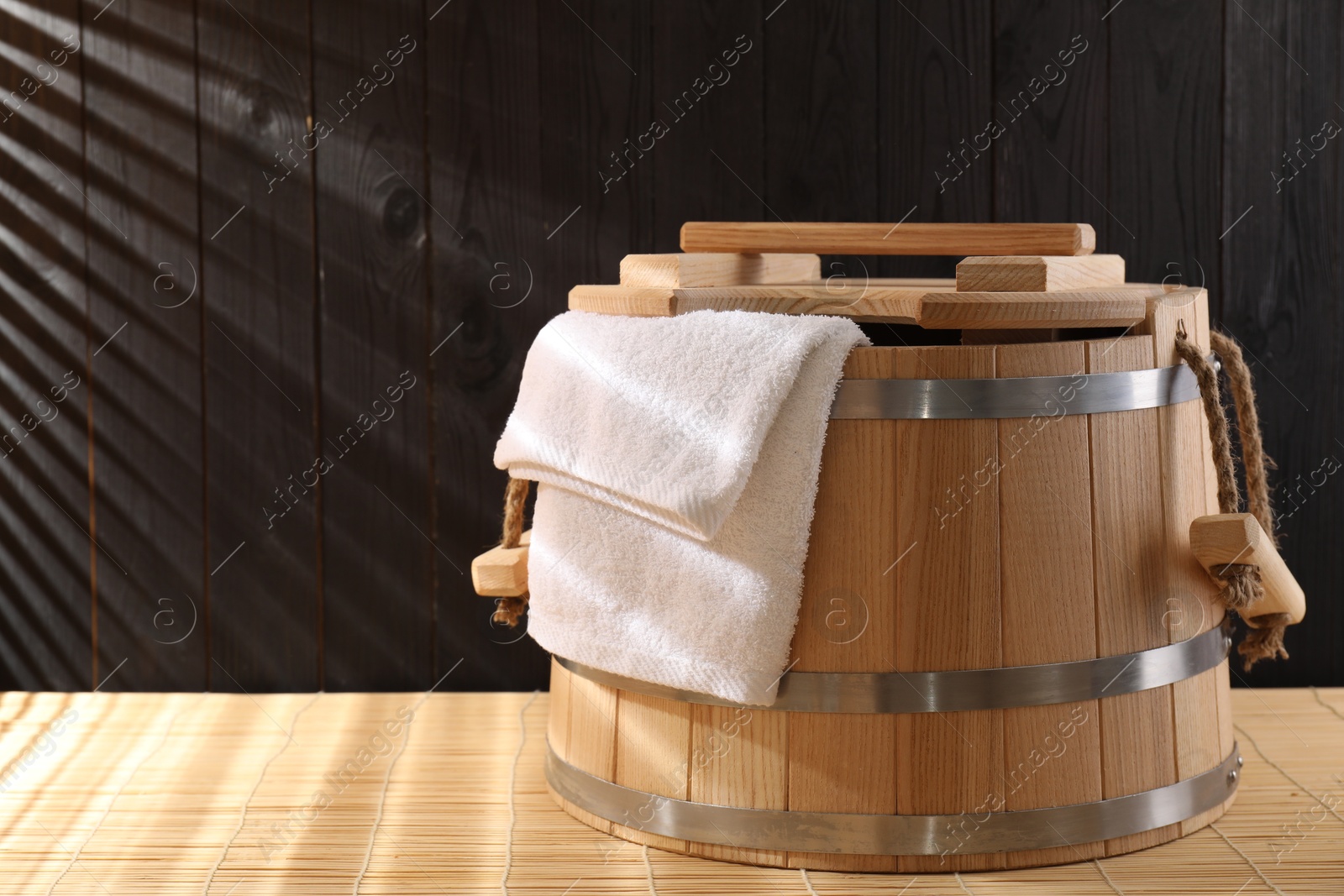 Photo of Sauna equipment. Bucket and towel on bamboo bench, space for text