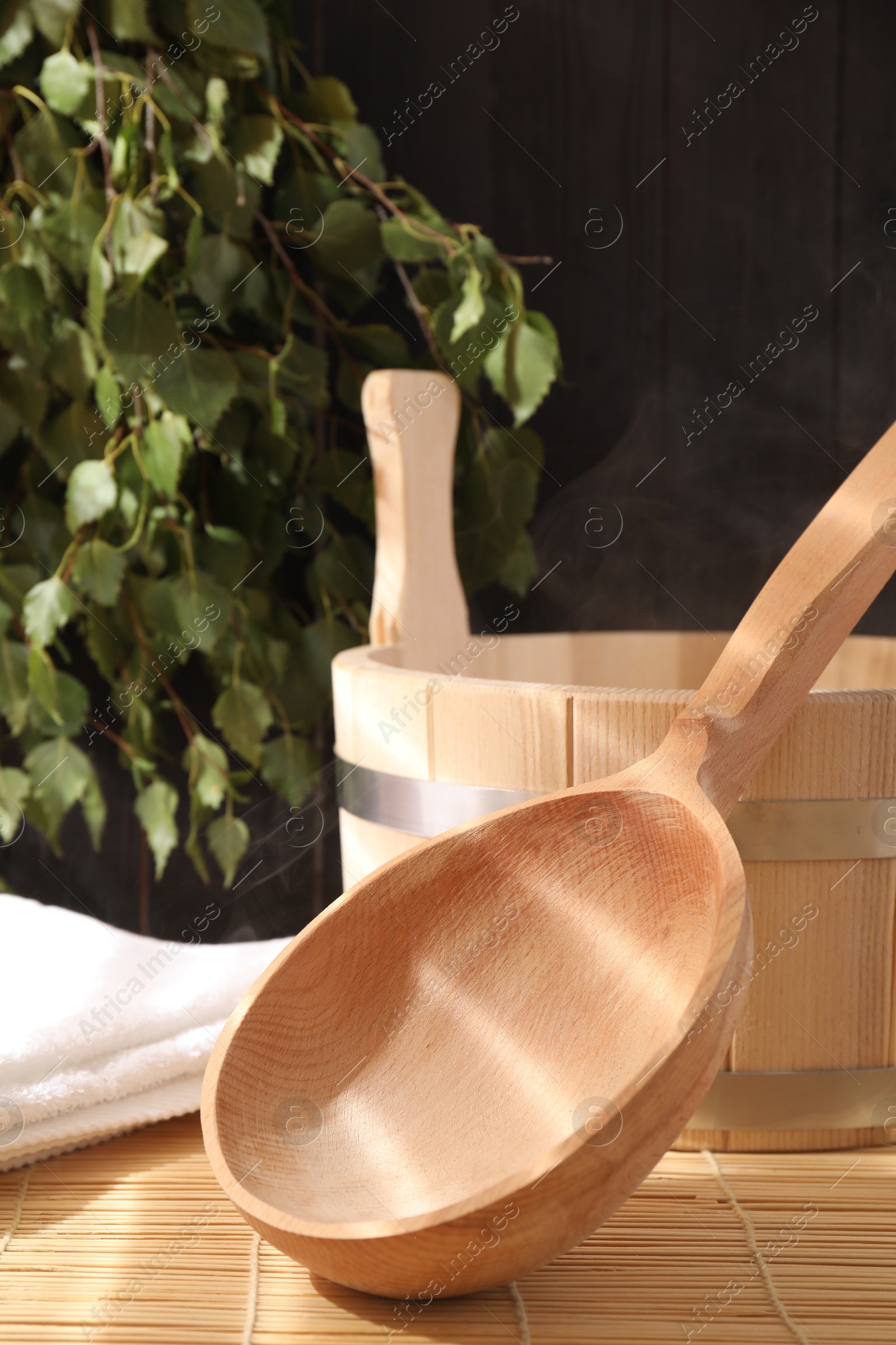 Photo of Sauna equipment. Bucket, ladle and towel on bamboo bench, closeup