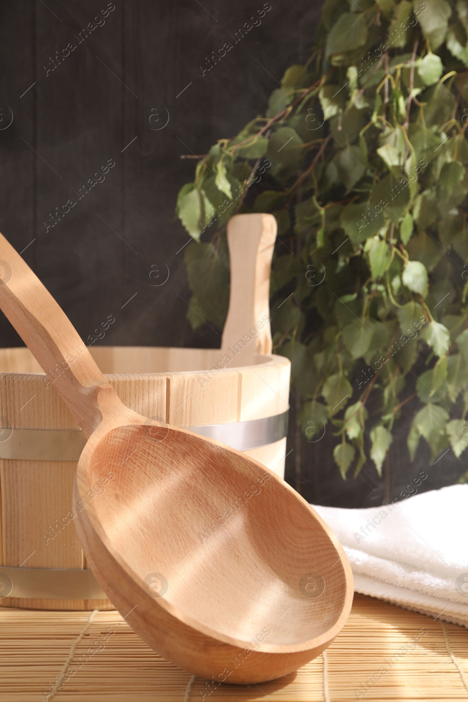 Photo of Sauna equipment. Bucket, ladle and towel on bamboo bench, closeup