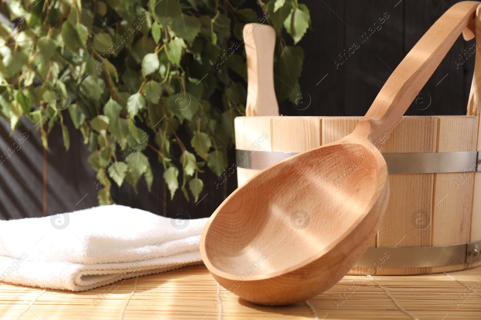 Photo of Sauna equipment. Bucket, ladle and towel on bamboo bench