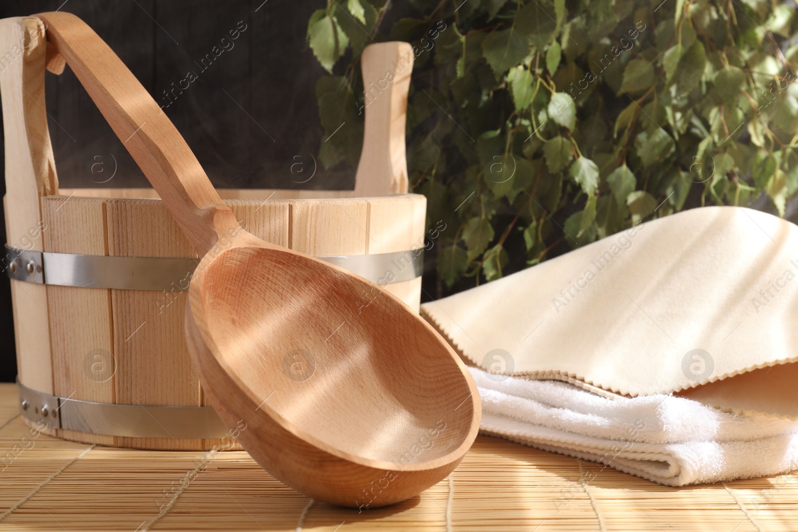 Photo of Sauna equipment. Bucket, ladle, felt wool hat and towel on bamboo bench