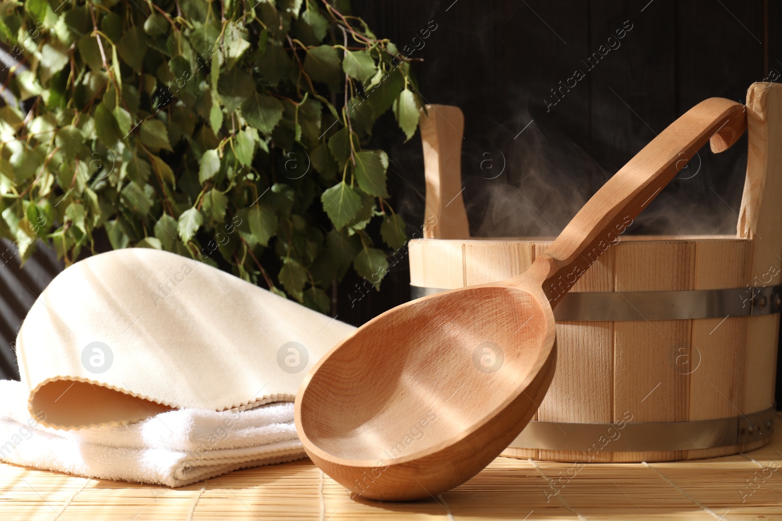 Photo of Sauna equipment. Bucket, ladle, felt wool hat and towel on bamboo bench