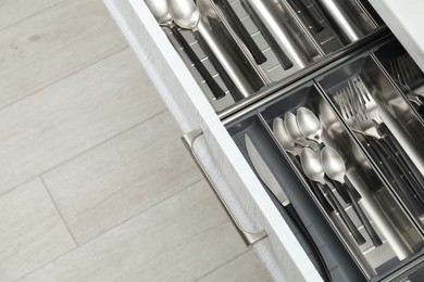 Photo of Box with cutlery in drawer, above view. Kitchen utensils storage