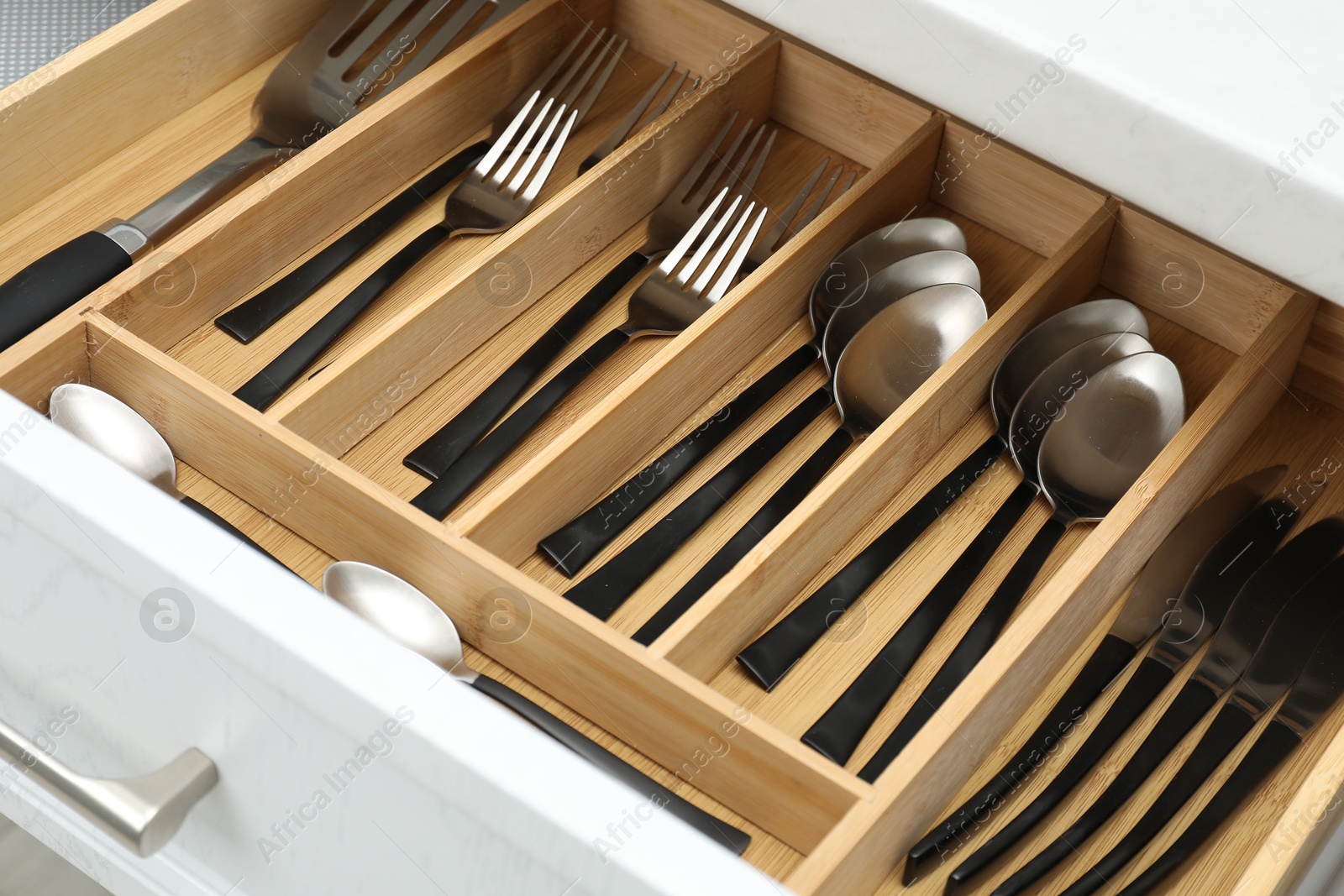 Photo of Box with cutlery in drawer, closeup. Kitchen utensils storage