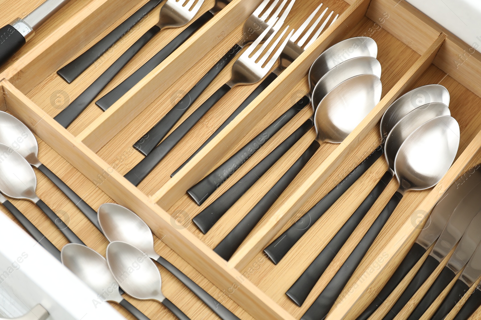 Photo of Box with cutlery in drawer, above view. Kitchen utensils storage