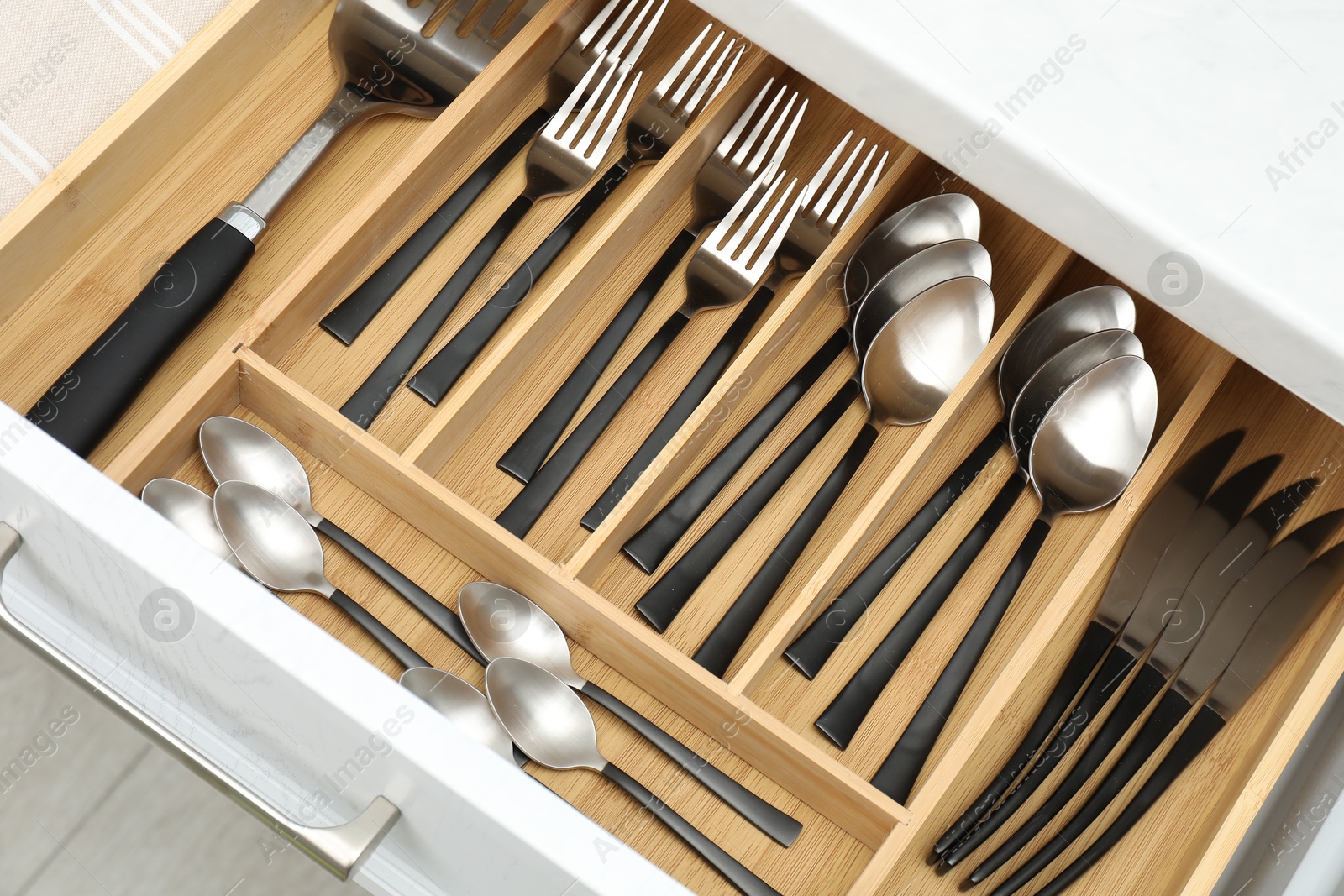 Photo of Box with cutlery in drawer, above view. Kitchen utensils storage