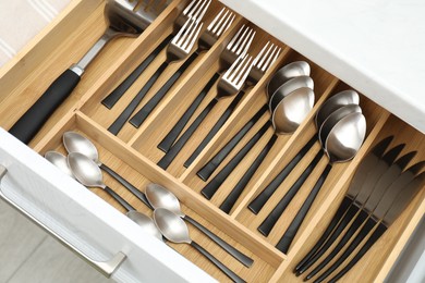 Photo of Box with cutlery in drawer, above view. Kitchen utensils storage