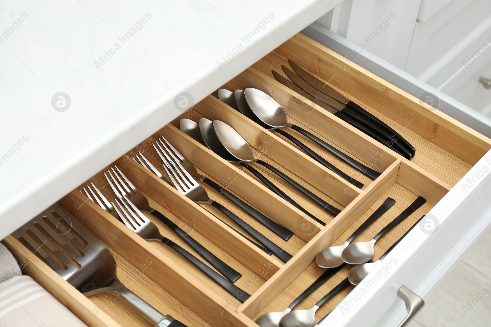 Photo of Box with cutlery in drawer, closeup. Kitchen utensils storage