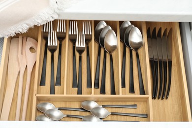 Photo of Box with cutlery in drawer, above view. Kitchen utensils storage