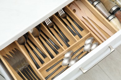 Photo of Box with cutlery in drawer, above view. Kitchen utensils storage