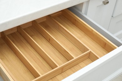 Photo of Open drawer of kitchen cabinet with space for cutlery, closeup