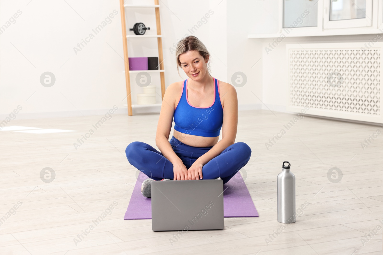 Photo of Online fitness trainer. Woman watching tutorial on laptop at home