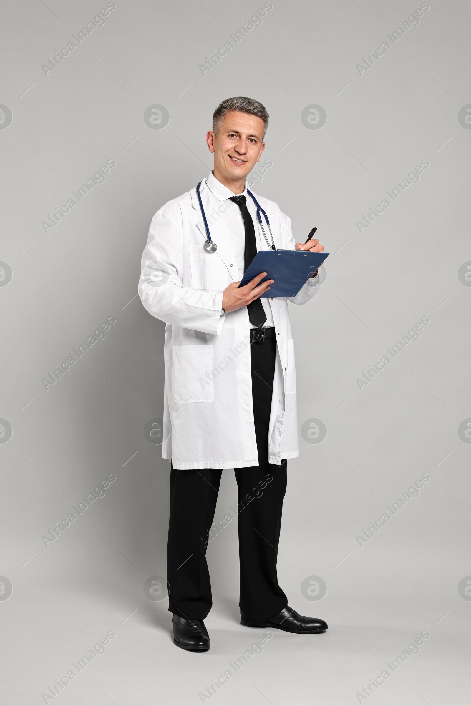 Photo of Doctor with stethoscope and clipboard on grey background