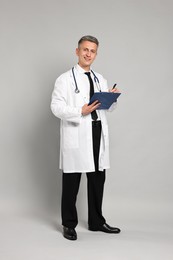 Photo of Doctor with stethoscope and clipboard on grey background