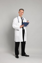 Doctor with stethoscope and clipboard on grey background