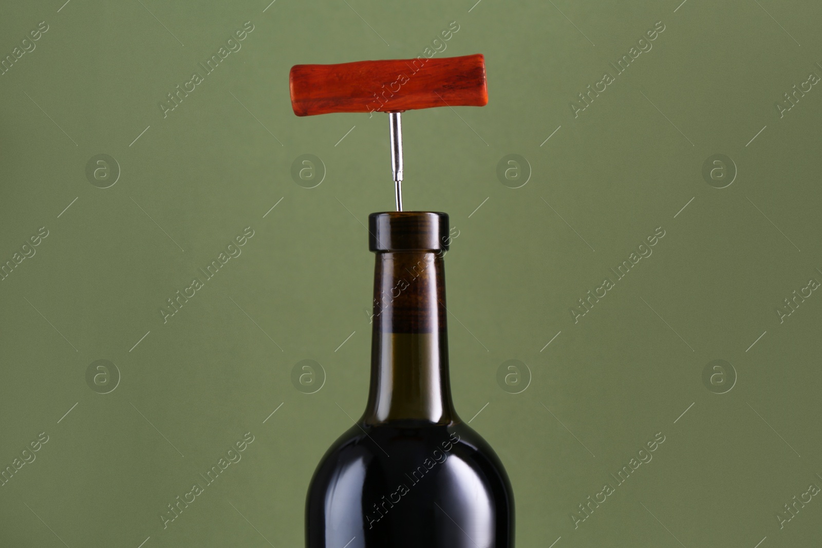 Photo of Wine bottle with corkscrew on olive background, closeup