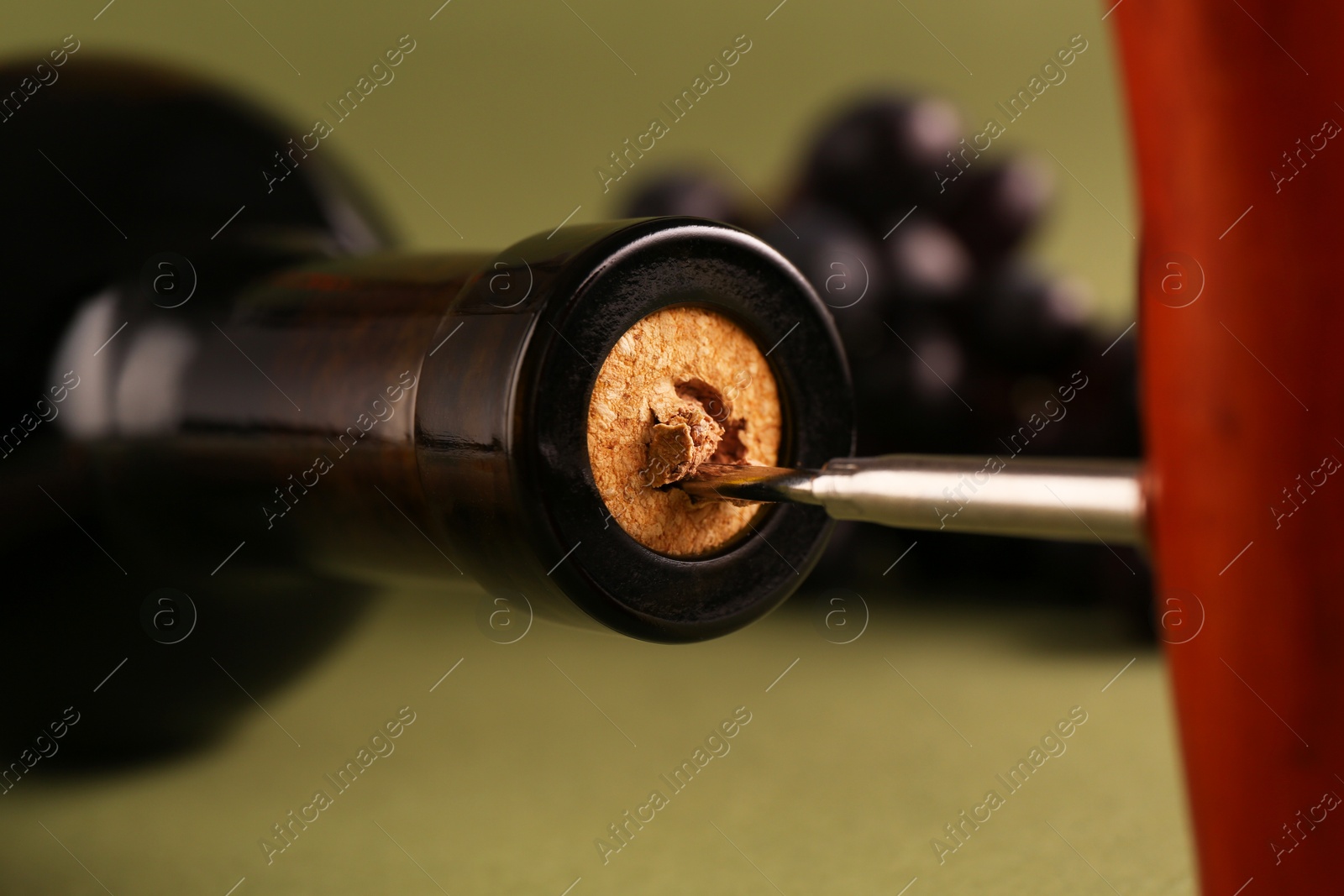 Photo of Wine bottle with corkscrew on olive background, closeup