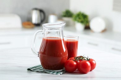 Tasty tomato juice in jug, glass and vegetables on white marble table