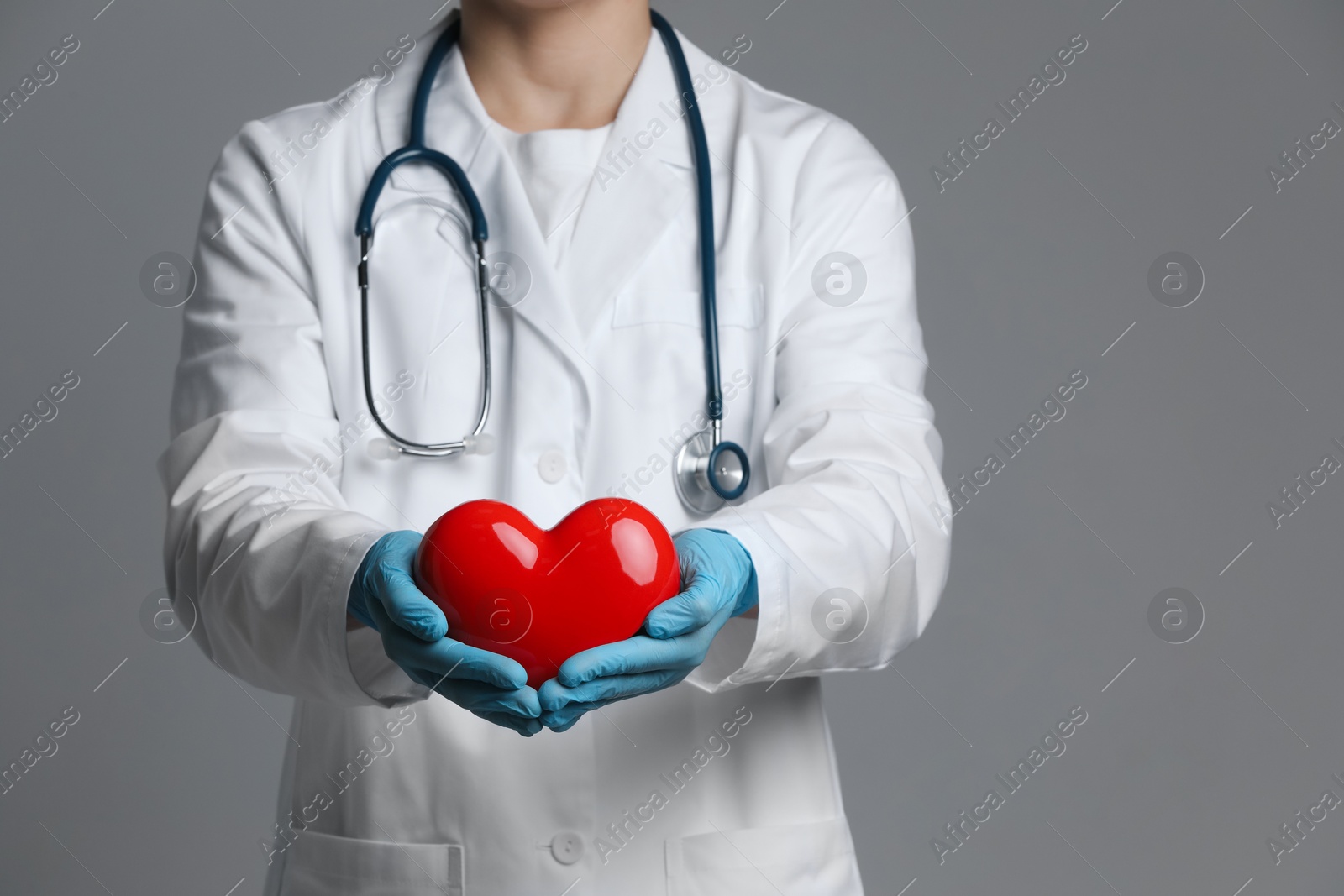 Photo of Doctor with red heart on grey background, closeup